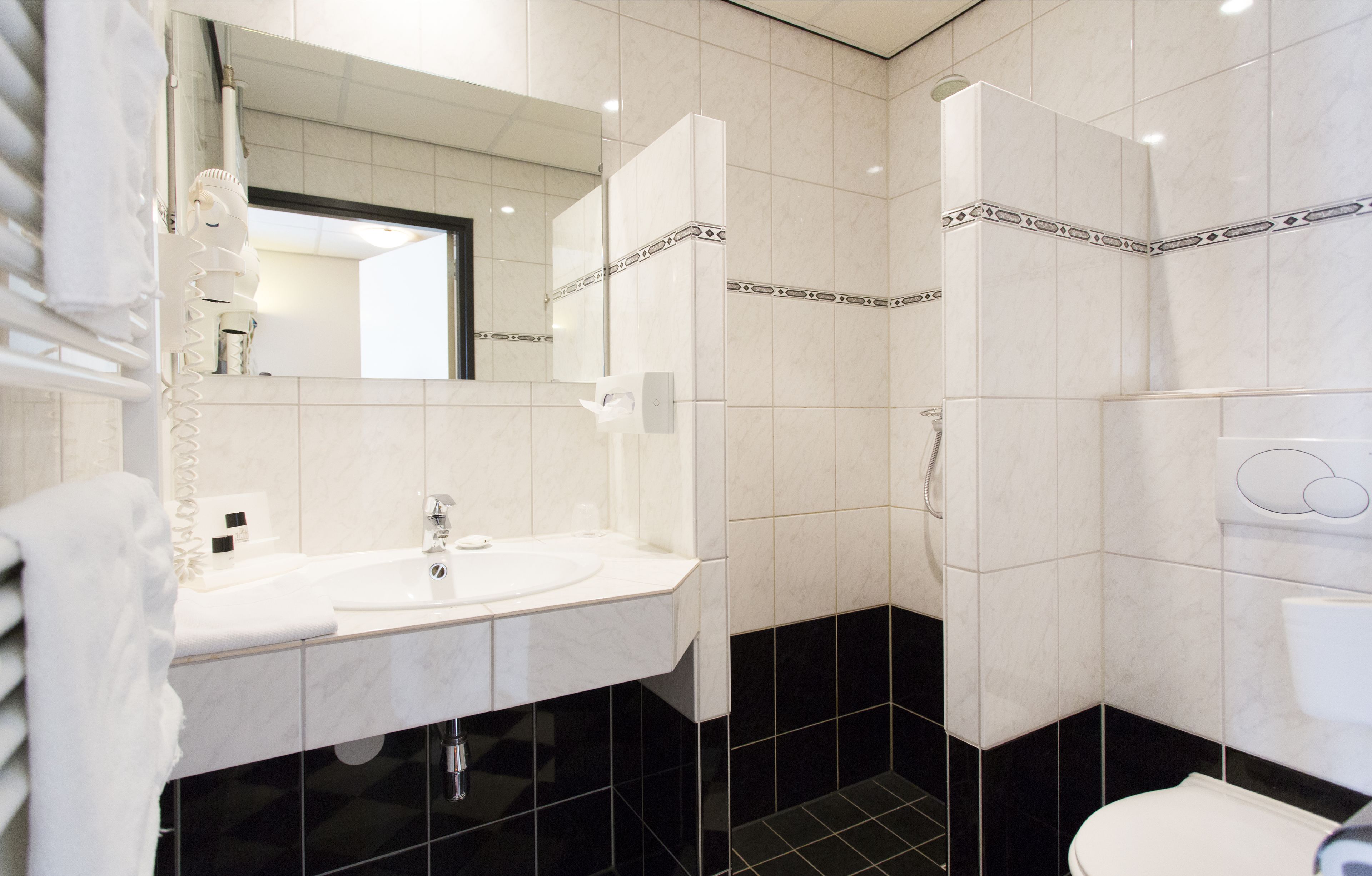 A modern bathroom with a white sink, mirror, and black-tiled floor.