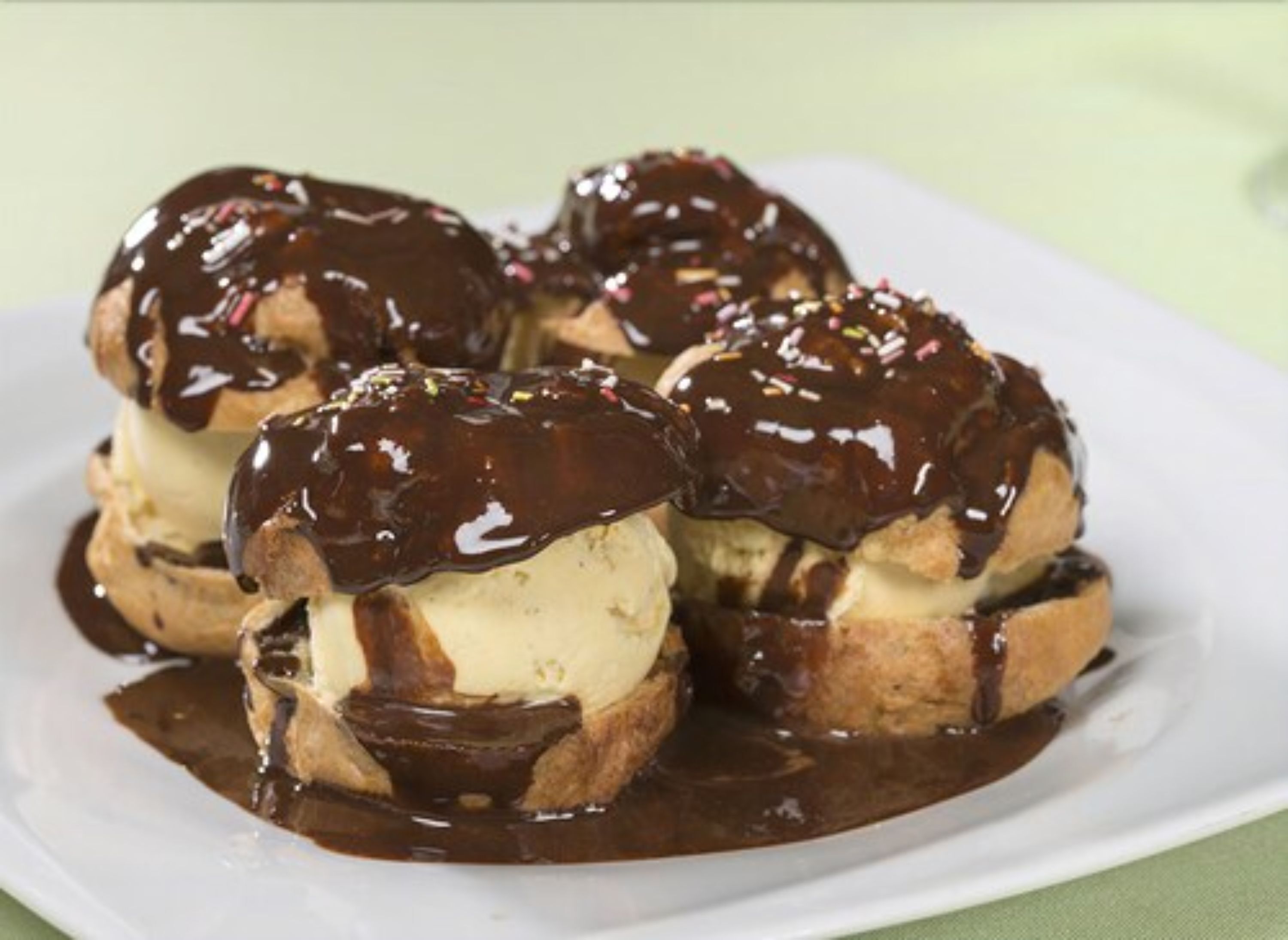 A plate of chocolate-covered ice cream cones with a glossy chocolate sauce.