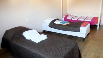 A room with two beds, one with a patterned bedspread and the other with a plain white bedspread.