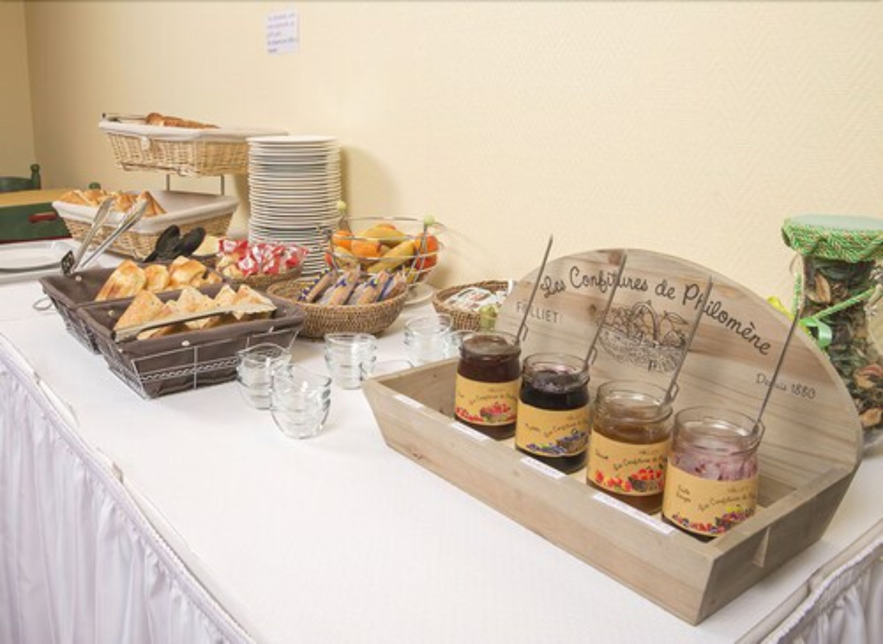 A buffet table with various food items, including bread, pastries, and jars of preserves.