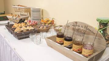 A buffet table with various food items, including bread, pastries, and jars of preserves.