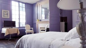 A bedroom with a bed, a chair, a desk with a lamp, and a television. - Hôtel Restaurant le Pan de Bois (Breviandes)