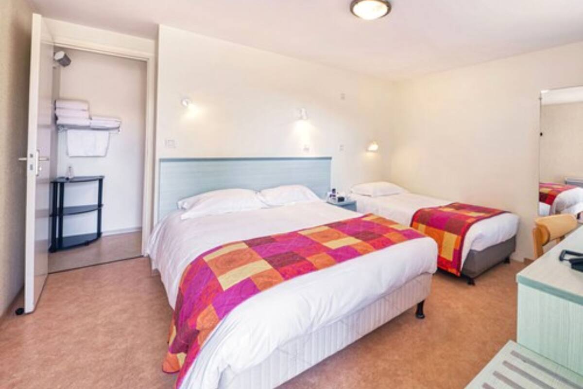A hotel room with two beds, a desk, and a chair.