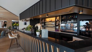 A modern bar area with a counter, stools, and a variety of bottles and glasses.