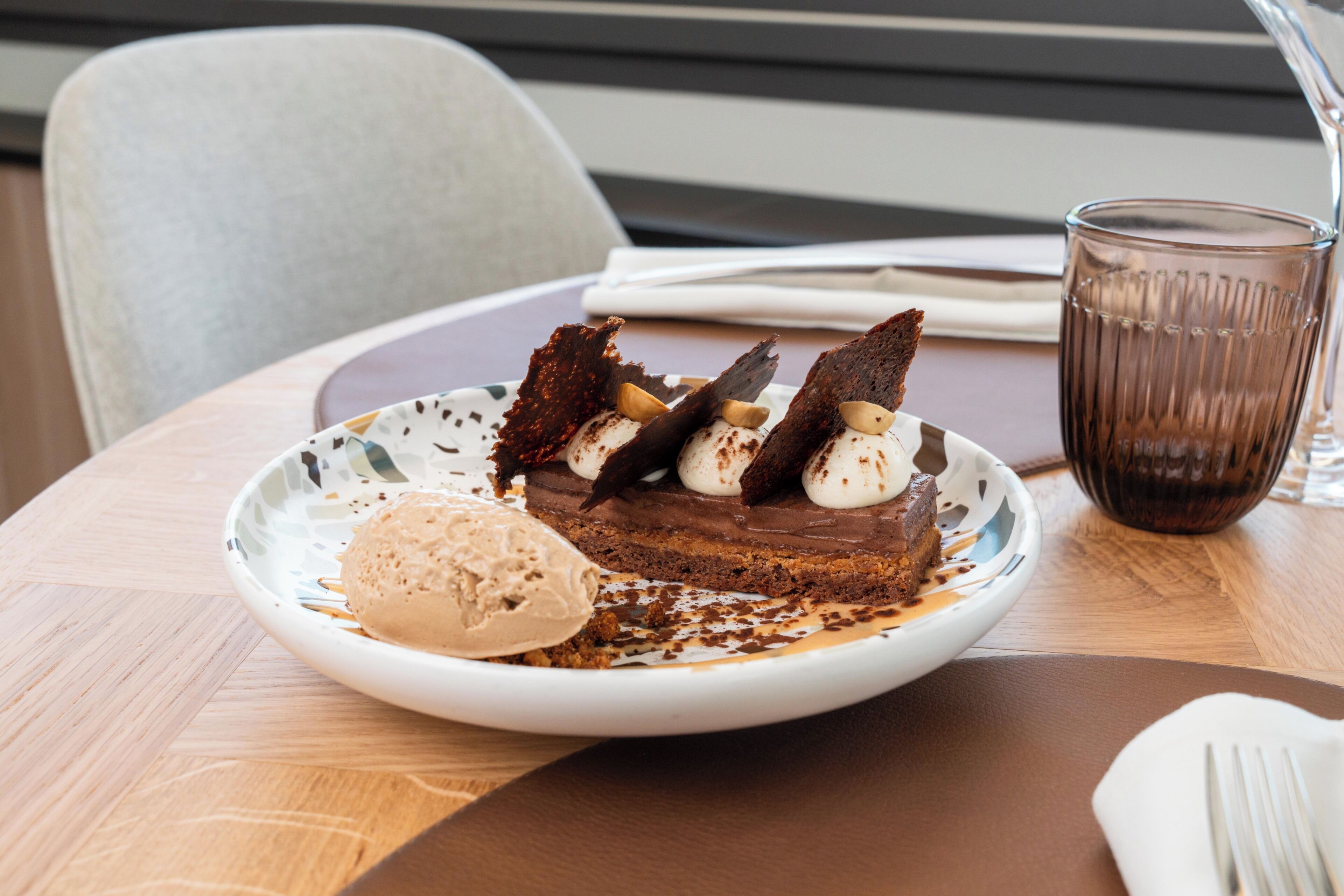 Un plato de postre con pastel de chocolate, helado y nueces sobre una mesa.