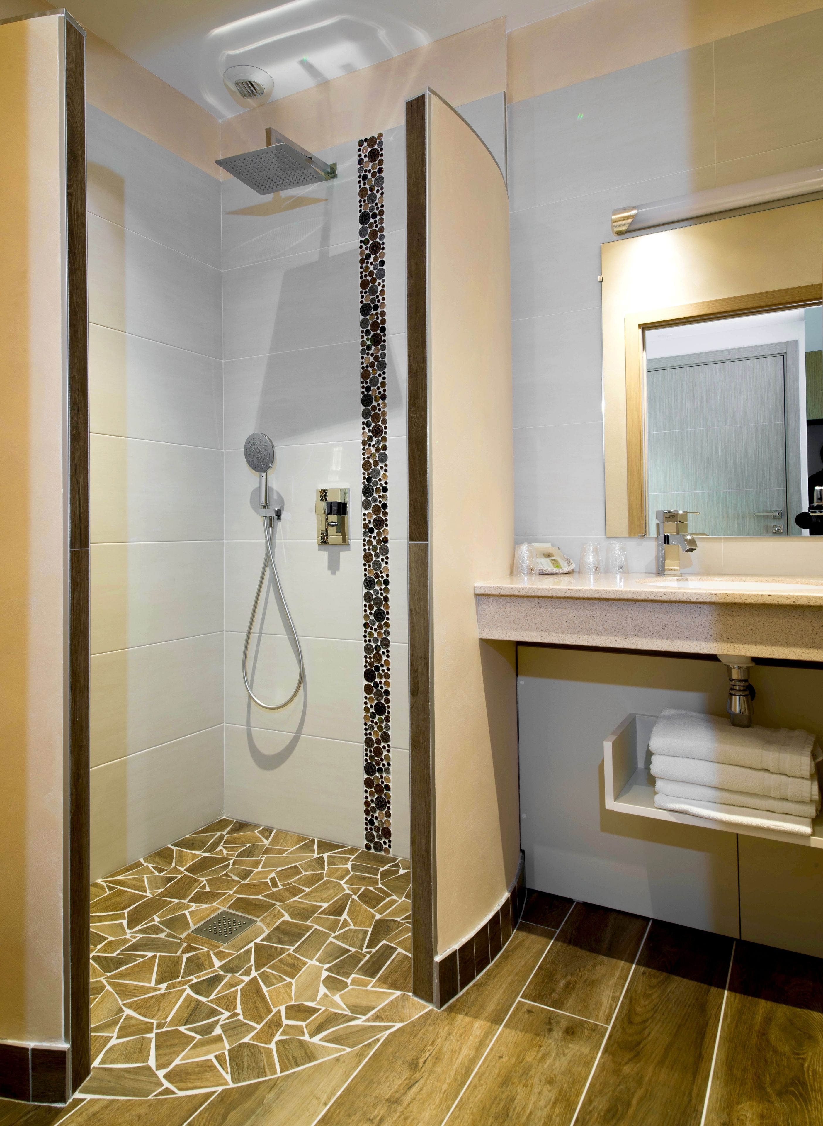Een moderne badkamer met een douche, wastafel en spiegel.