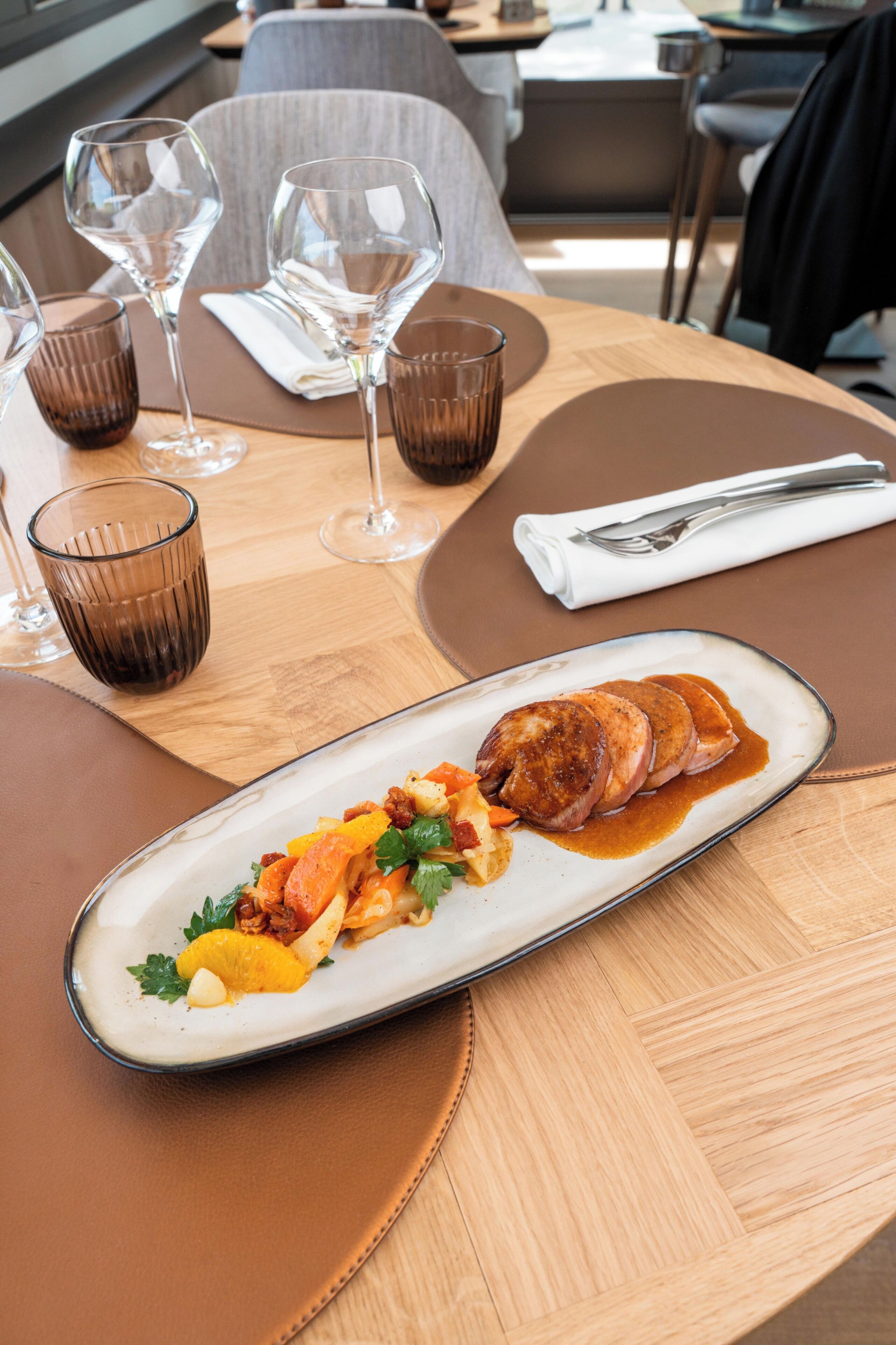 Une table à manger avec une assiette de nourriture, des verres et des couverts.