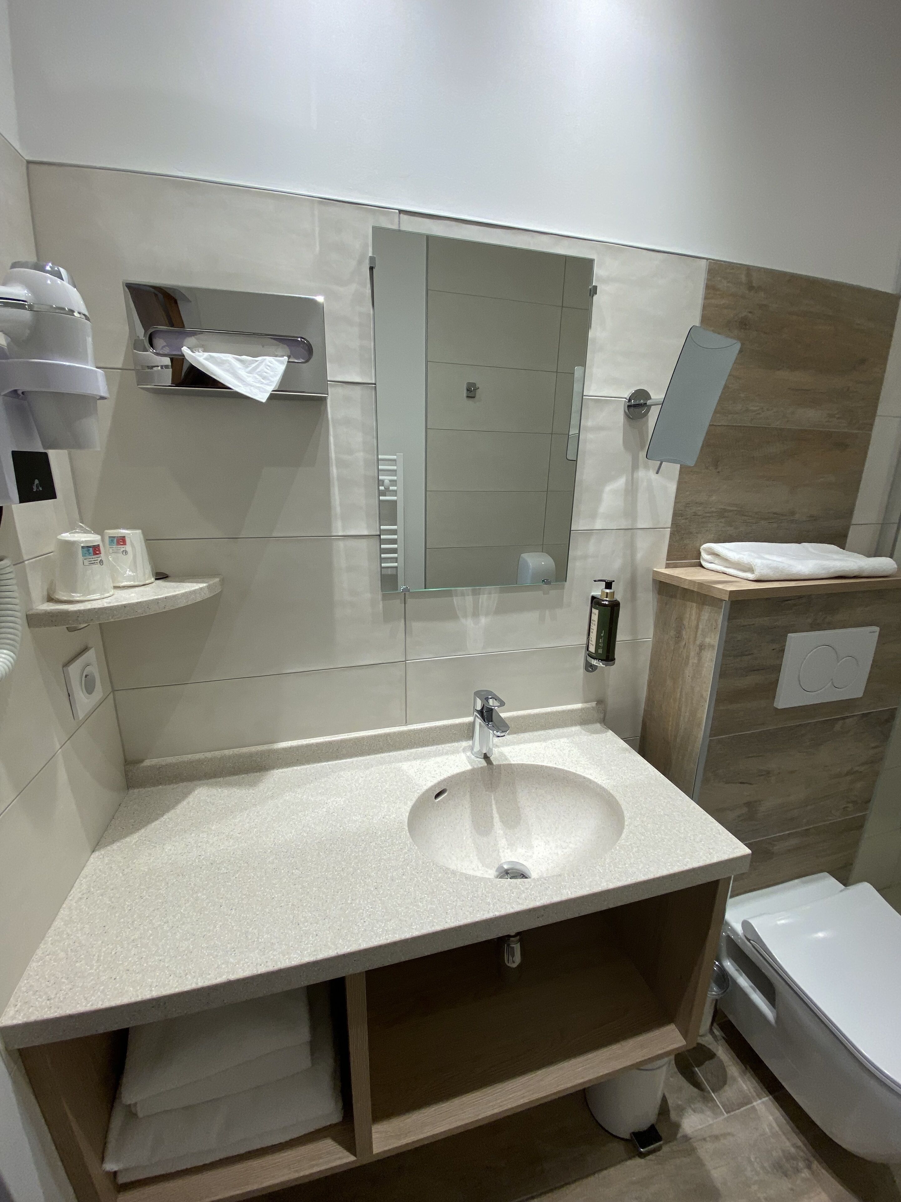 Un baño moderno con lavabo, espejo, toallero y retrete.