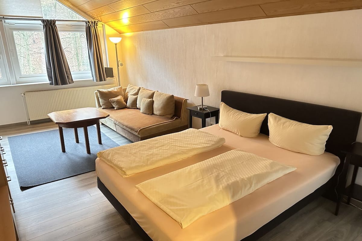 Une chambre d’hôtel avec un grand lit, un canapé, une petite table et une lampe.