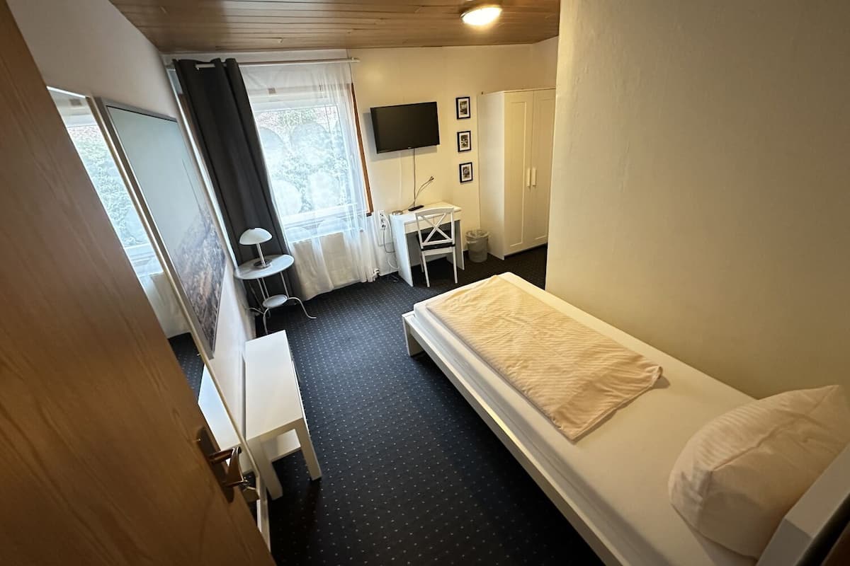 Une chambre d’hôtel équipée d’un lit, d’un bureau, d’une chaise, d’une télévision et d’une armoire.