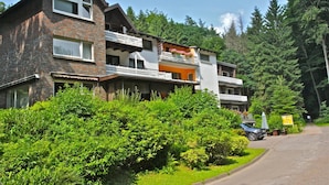 A multi-story building with balconies, surrounded by lush greenery and trees. - Waldhotel Porta Westfalica garni (Porta Westfalica)