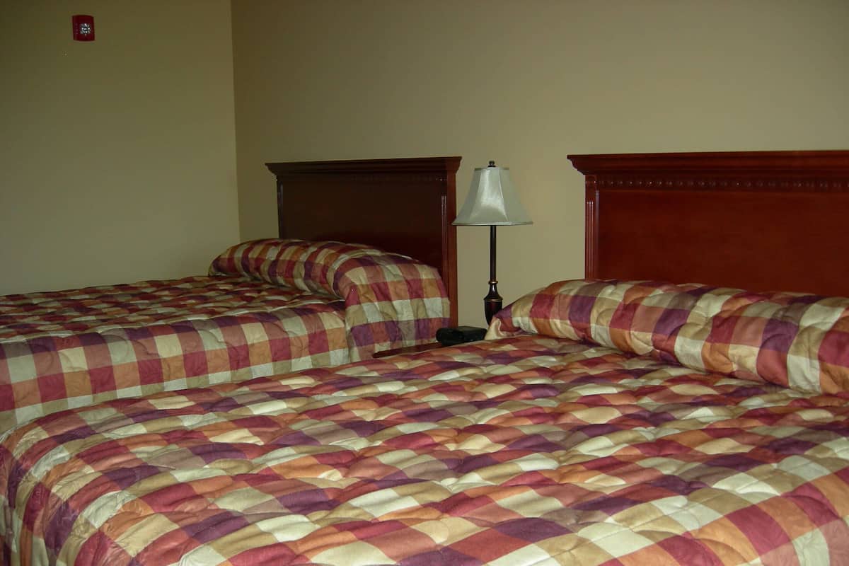A hotel room with two beds, each with a checkered bedspread and wooden headboards.