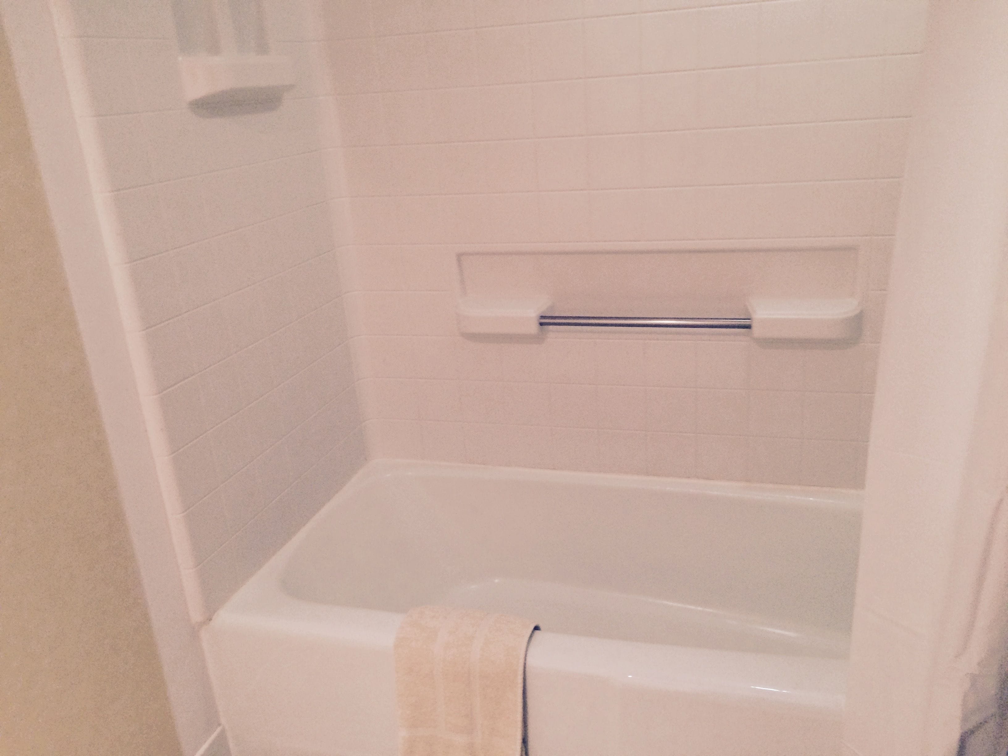 A bathroom with a bathtub, a towel rack, and a showerhead.