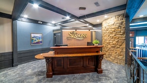 A reception desk with a stone wall and a sign that reads "The Seasons Lodge". - The Seasons Lodge (Nashville)