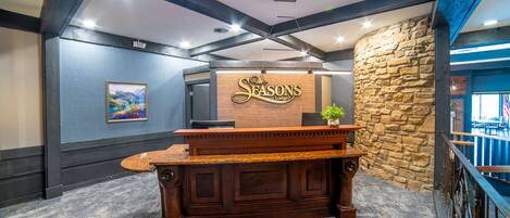 Ein Empfangstresen mit einer Steinwand und einem Schild mit der Aufschrift 'The Seasons Lodge'.