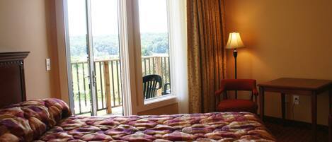 Une chambre d’hôtel avec un grand lit, une chaise, une table et une vue sur un balcon également équipé d’une chaise.