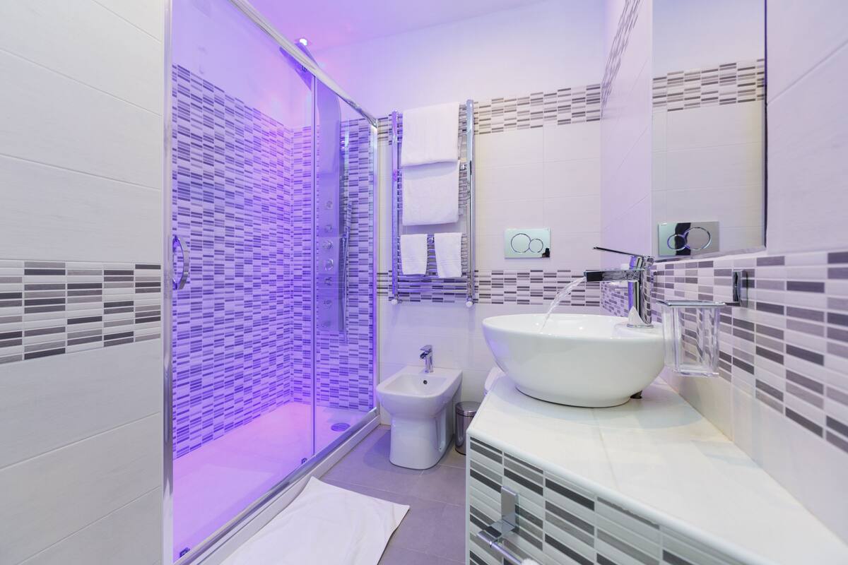 A modern bathroom with a glass-enclosed shower, a white sink, and a bidet.