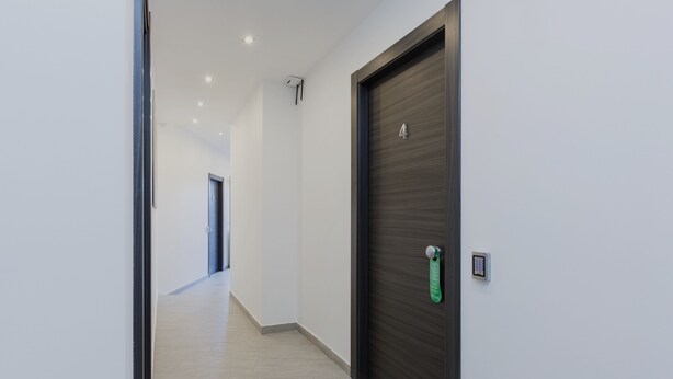 A modern hallway with a dark wooden door, a keypad lock, and a light-colored tiled floor. - Domus Arena (Rome)