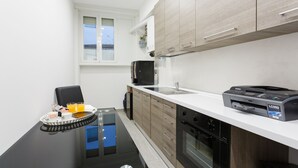 A modern kitchen with a black countertop, wooden cabinets, a built-in oven, and a coffee machine. - Domus Arena (Rome)