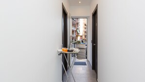 A narrow hallway with a metal rack holding a basket and a glass of orange juice. - Domus Arena (Rome)