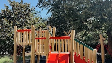 Kids can climb and slide in this playground area surrounded by trees.