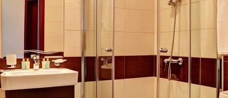 Un baño moderno con ducha envuelta en vidrio, tocador con espejo y un inodoro.