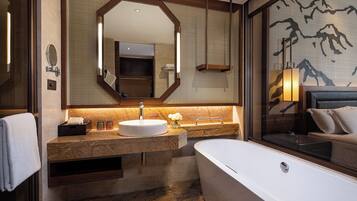 A modern bathroom with a freestanding bathtub, a large mirror, and a vanity with a sink and countertop.