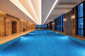 A long indoor swimming pool with a tiled floor and walls, large windows on one side, and a modern ceiling design. - Crowne Plaza Resort Changbaishan Hot Spring by IHG (Yanbian)