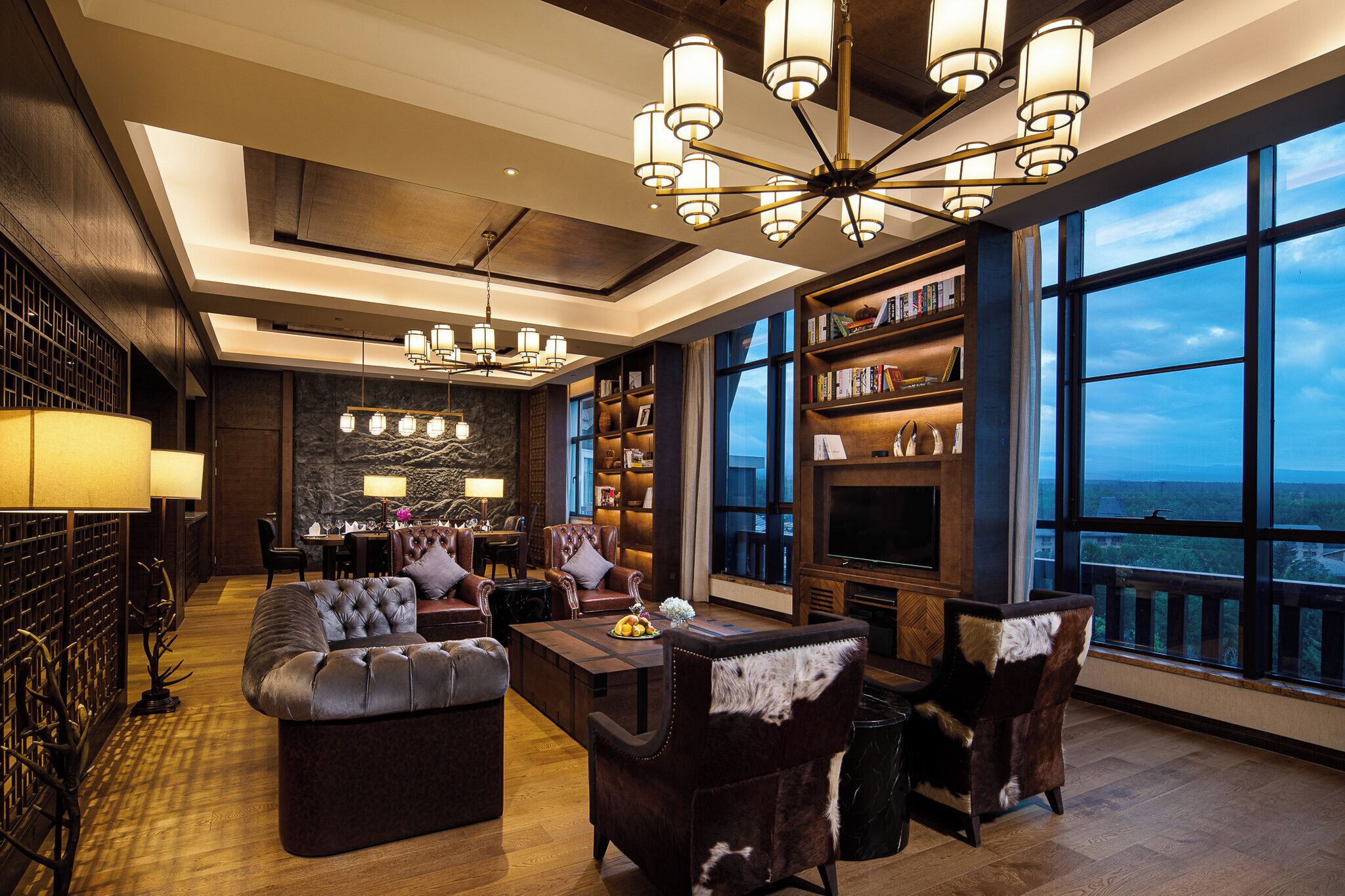 A spacious lounge with leather sofas, a coffee table, and a large bookshelf.