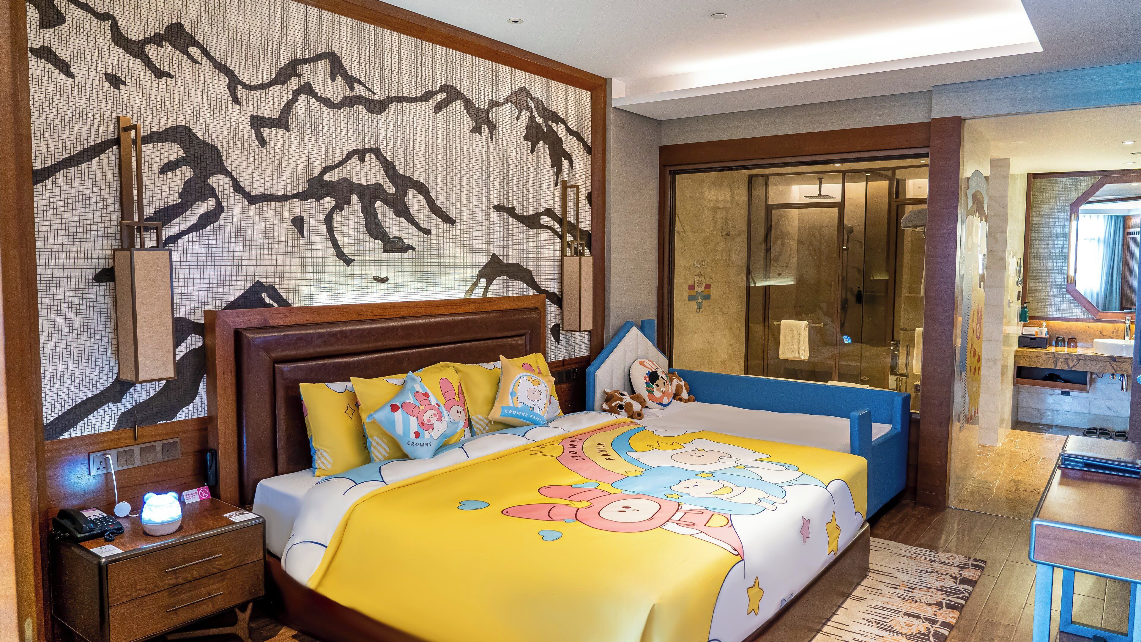 A hotel room with a bed, bedside table, and a large mirror.