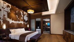 Ein modernes Hotelzimmer mit einem großen Bett, einem Schreibtisch und einem durchgehenden Türspalt sichtbaren Badezimmer.