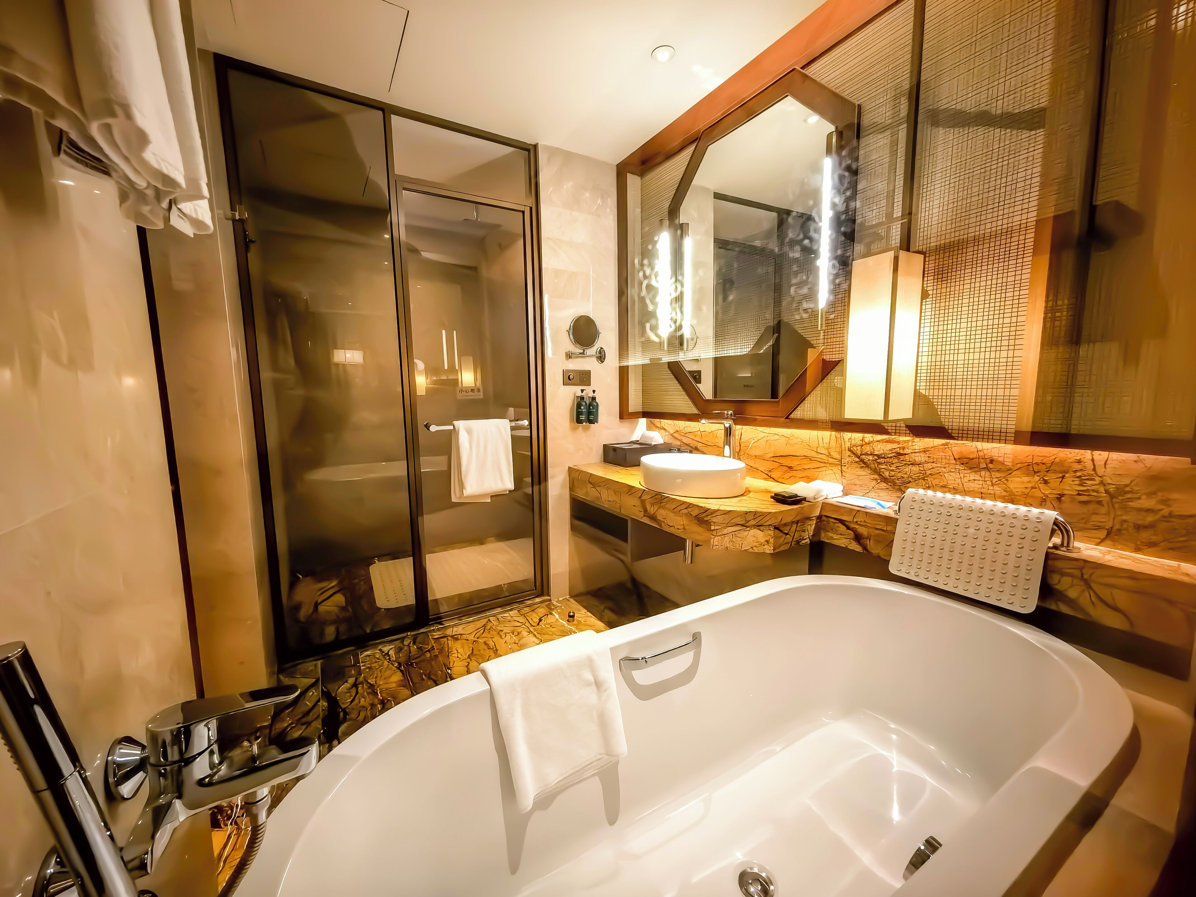 Une salle de bain moderne dotée d’une douche à parois de verre, d’une baignoire sur pieds et d’un meuble-lavabo avec un plan de travail en marbre.
