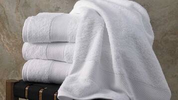 A stack of white towels on a chair with a textured wall in the background.