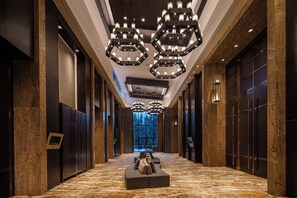 A long hallway with a marble floor, large wooden doors, and a central seating area with cushions. - Crowne Plaza Resort Changbaishan Hot Spring by IHG (Yanbian)
