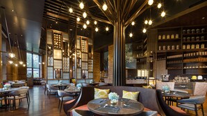 Ein modernes Restaurantambiente mit runden Tischen, gepolsterten Sitzgelegenheiten und hängenden Leuchten.