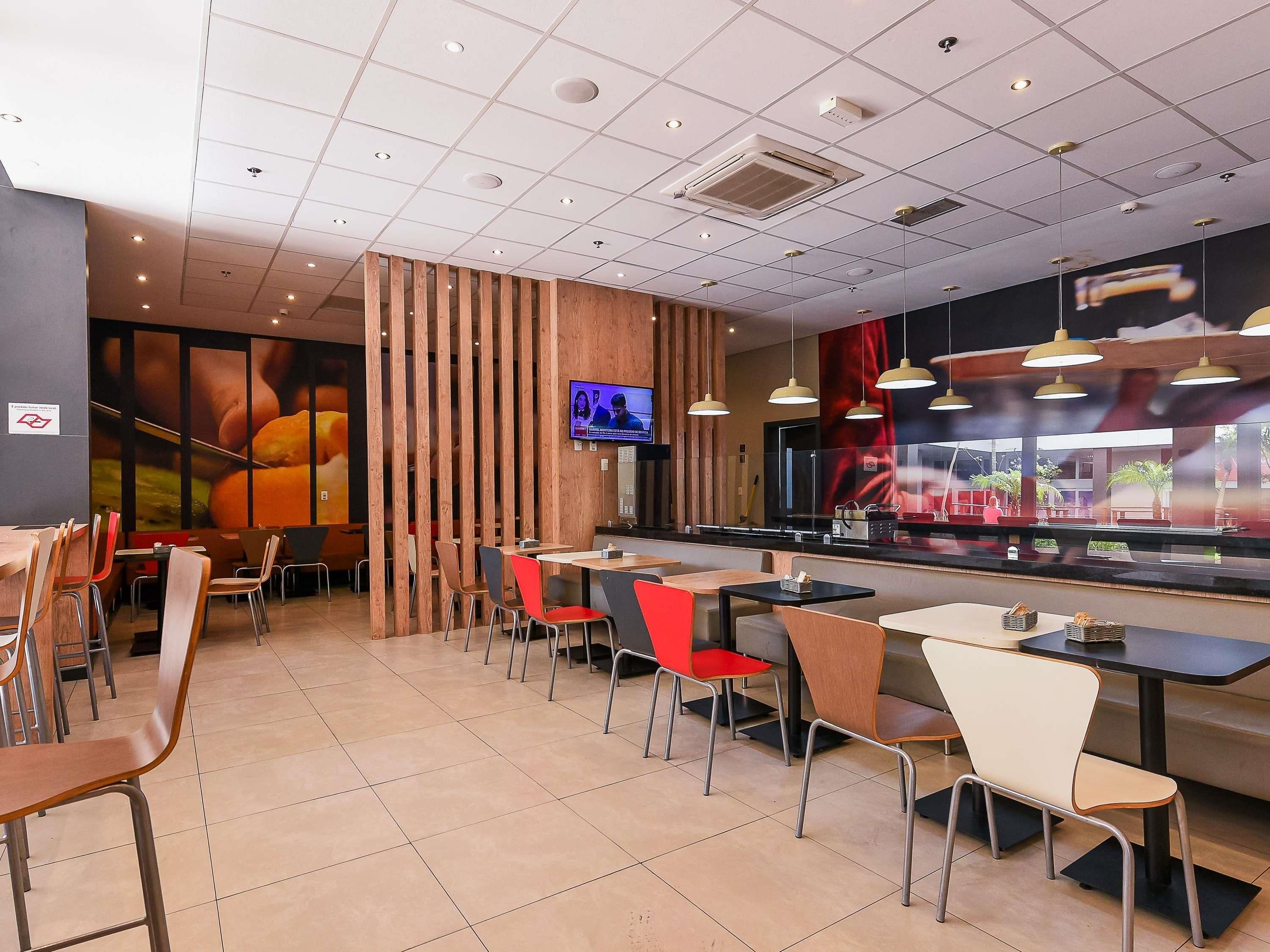 A restaurant interior with a tiled floor, wooden partitions, and a variety of chairs and tables.