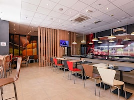 Interior de restaurante con suelo de baldosas, separadores de madera y diferentes sillas y mesas.