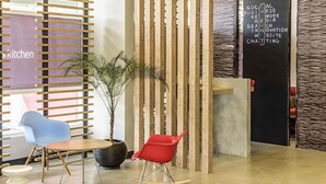 A modern reception area with a wooden slatted partition, a potted plant, and two chairs. - ibis Jacarei (Jacarei)