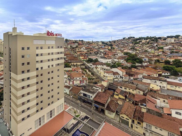 A hotel with multiple floors, a rooftop pool, and a view of a densely packed urban area with terracotta-roofed buildings. - ibis Jacarei (Jacarei)