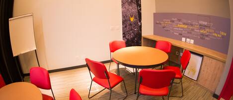 A conference room with a round table, red chairs, a whiteboard, and a wall with motivational words.
