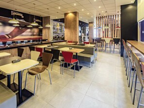 Un restaurante moderno con área de bar, cabinas y mesas altas.