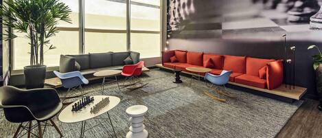 A modern lounge area with a sectional sofa, a coffee table, and a chessboard.