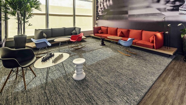 A modern lounge area with a large window, a red sofa, a blue chair, and a chessboard. - ibis Jacarei (Jacarei)