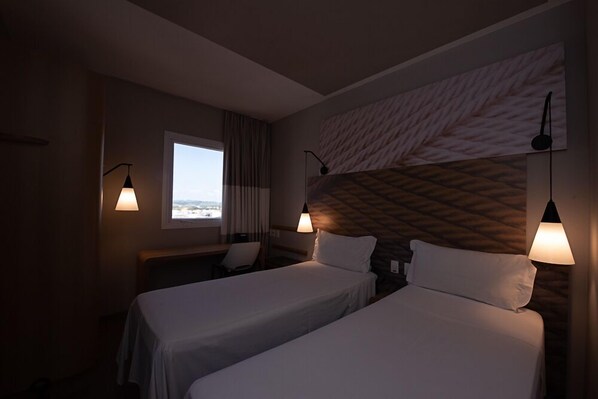 A hotel room with two beds, a window with a view, and a patterned headboard. - ibis Jacarei (Jacarei)