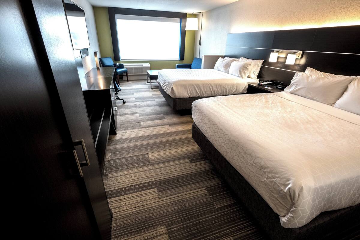 A hotel room with two beds, a desk, and a chair.