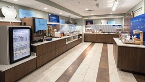 Un espace moderne dédié au petit-déjeuner, doté d’un écran numérique affichant le menu, d’un distributeur de boissons en libre-service et proposant une variété de plats.