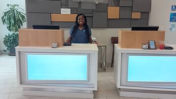 A reception desk with a modern design, a potted plant, and a sign indicating a Holiday Inn Express.