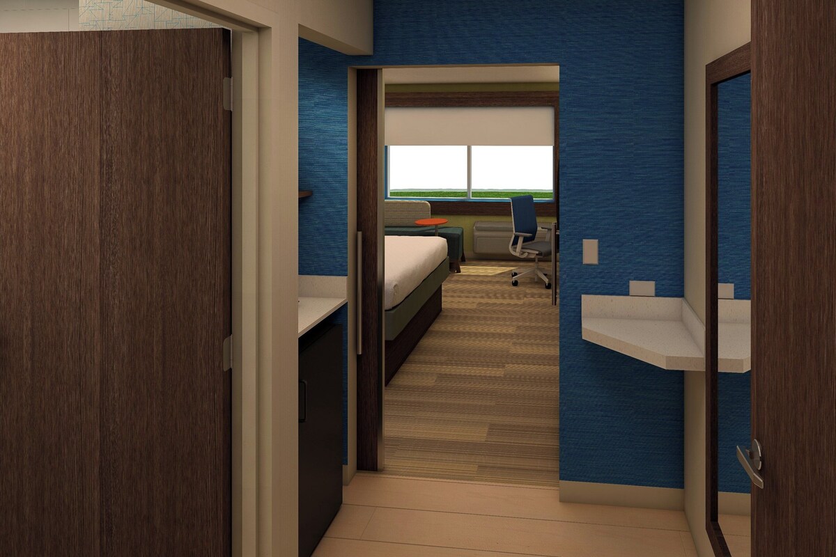 Une chambre d’hôtel avec un lit, un bureau et une chaise. Il y a une fenêtre donnant sur l’extérieur.