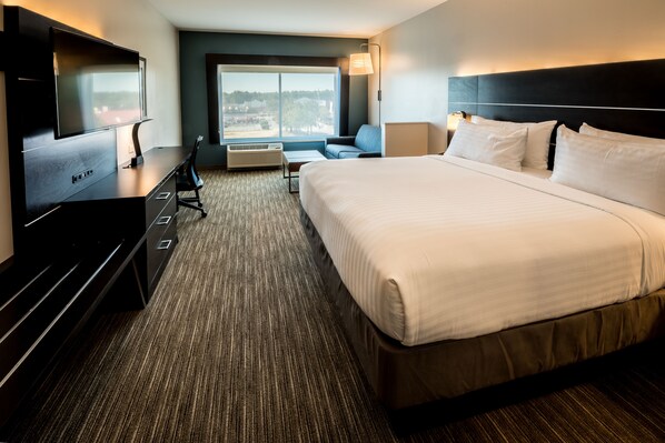 A hotel room with a large bed, a flat-screen TV, a desk, and a window with a view of the city. - Holiday Inn Express North Augusta by IHG (North Augusta)
