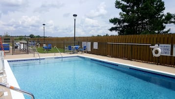 Una piscina con azulejos azules, una valla de madera y señales que indican poca profundidad y prohibido bucear.